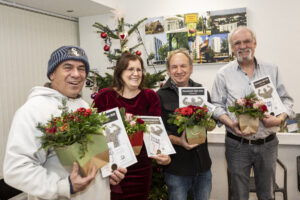 Alle vier Preisträger stehen in einem Halbkreis und lachen in die Kamera. In ihren linken Händen halten sie die bunten Blumensträuße, in der rechten Hand ihre Urkunden und Taler.