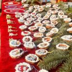 Auf einem Tisch mit roter Samtdecke und Tannengrün ist kleines Kunsthandwerk drapiert. In halben Walnussschalen sind kleine Figuren eingelassen wir Schneemänner, Engel und Weihnachtsmänner.