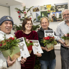Alle vier Preisträger stehen in einem Halbkreis und lachen in die Kamera. In ihren linken Händen halten sie die bunten Blumensträuße, in der rechten Hand ihre Urkunden und Taler.
