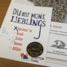 Foto einer Urkunde mit einem geprägten Taler mit der Aufschrift "Neuwieden - Taler 2022".